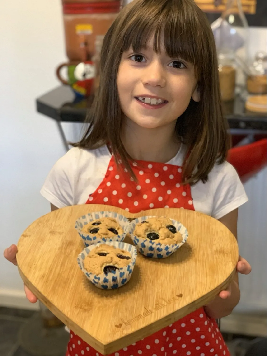 Criança segurando muffins de mirtilo